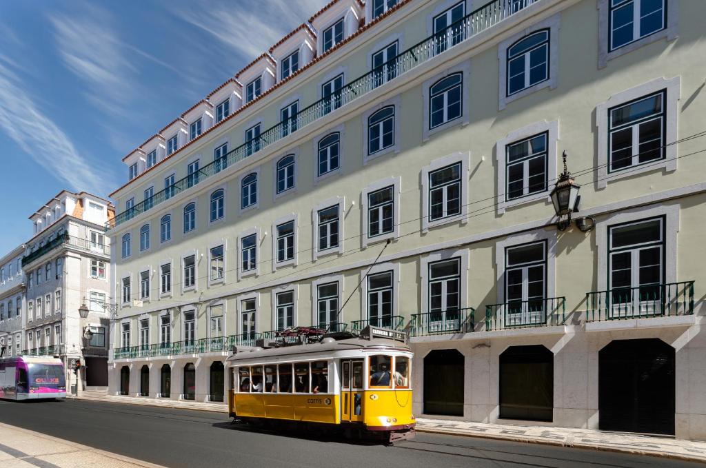里斯本Eurostars Lisboa Baixa的黄色电车驶过大建筑