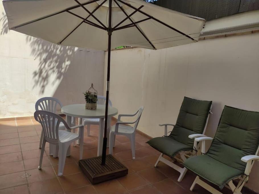 帕拉莫斯Cozy flat with terrace的桌椅、桌子和雨伞