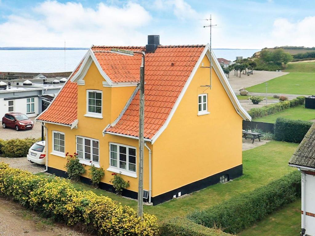 Tranekær6 person holiday home in Tranek r的黄色房子,有橙色屋顶