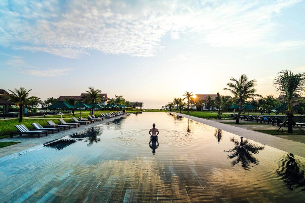 谭奎TUI BLUE Nam Hoi An Resort的一个人在度假村的游泳池里漫步