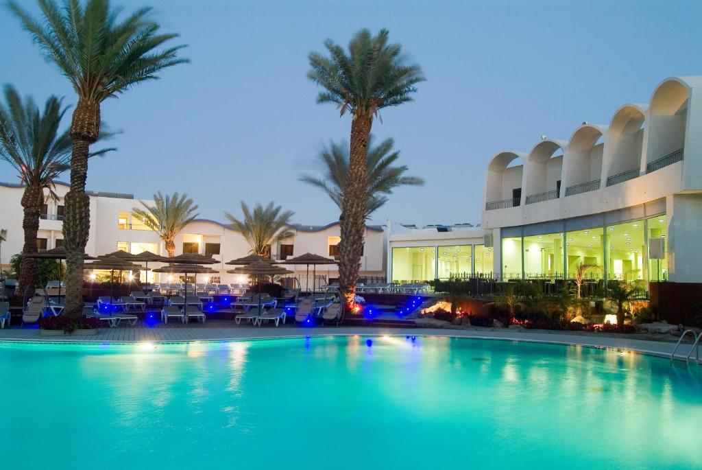 埃拉特莱昂纳多埃拉特全包酒店 的棕榈树建筑前的大型游泳池