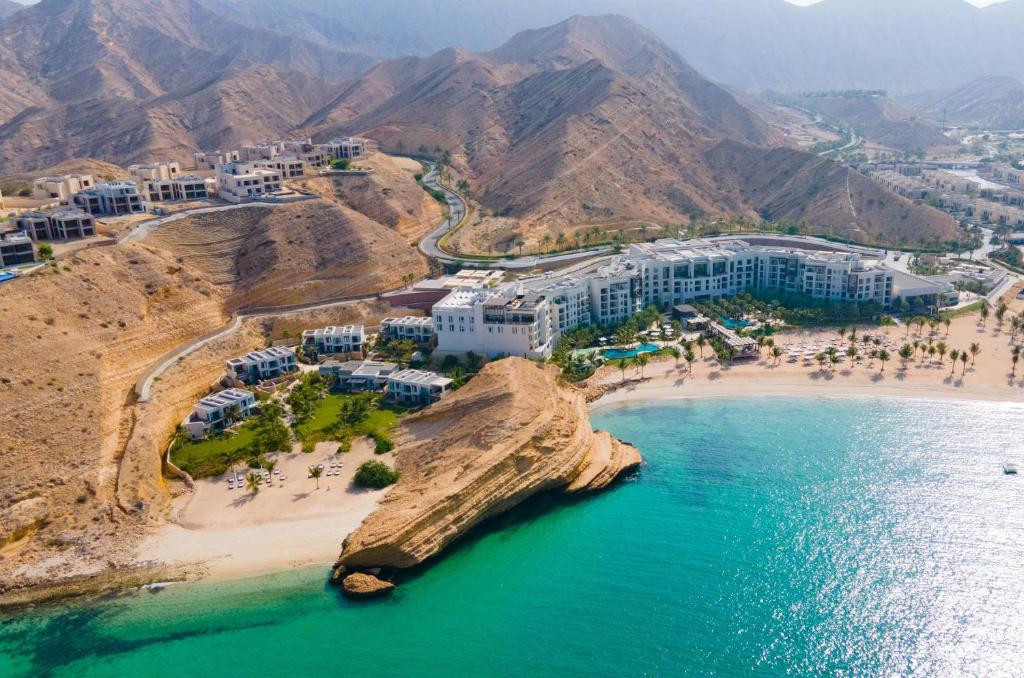 马斯喀特Jumeirah Muscat Bay Oman的享有海滩的空中景色,拥有人员和建筑