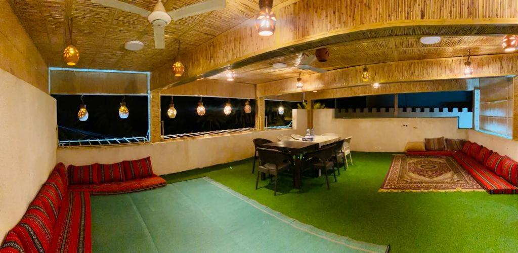 阿尔哈姆拉Sehma Guest House的一间设有一张桌子和红色沙发的客房,并铺有绿色地板。