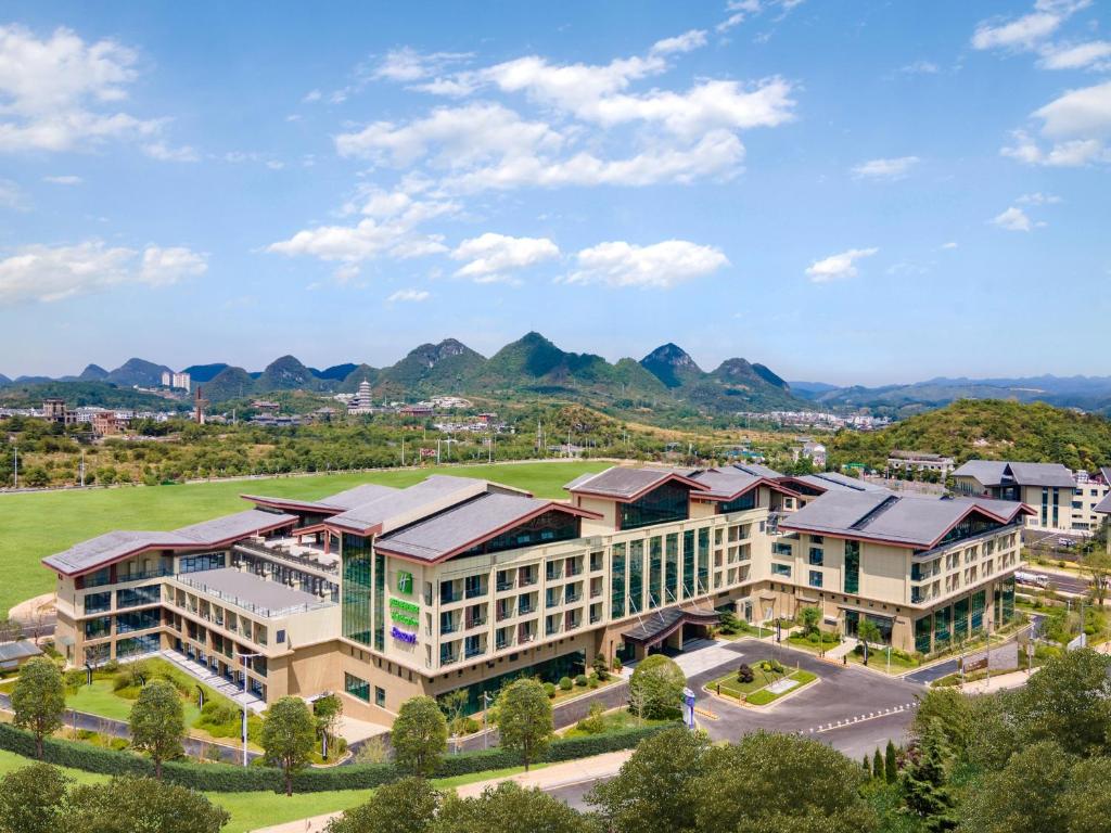 贵阳贵阳青岩假日度假酒店的享有建筑的空中景观,以群山为背景
