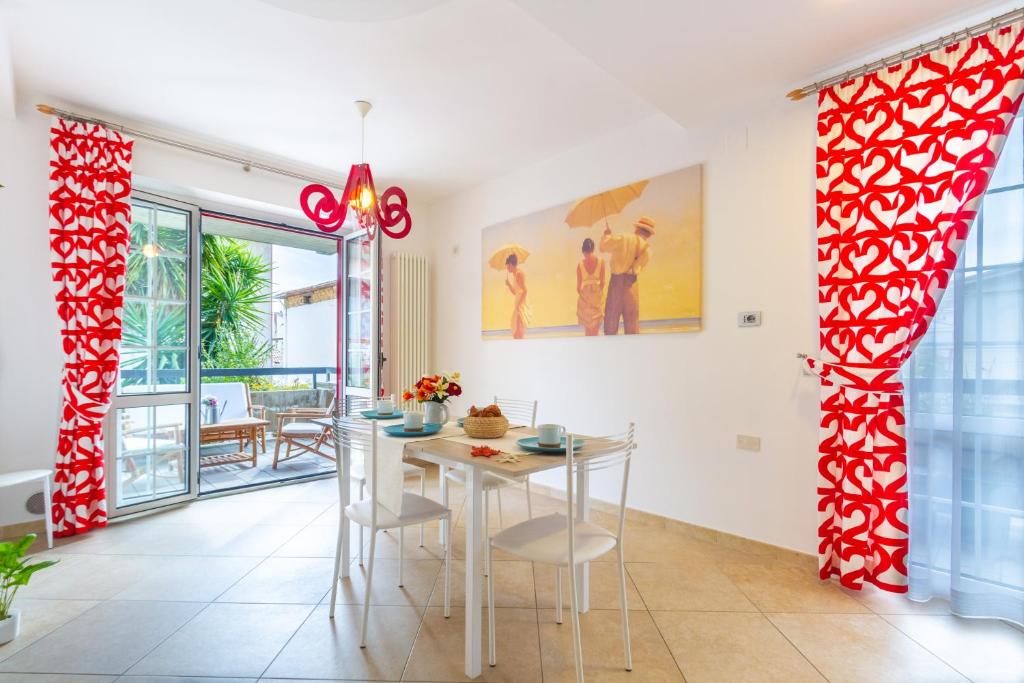 马帝斯兹罗Appartamento Bellaria Luxury - MyHo Casa的一间拥有红色和白色窗帘及桌椅的用餐室