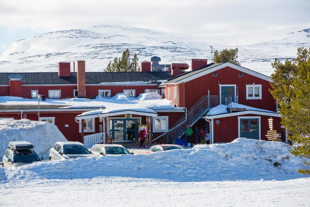 格勒韦尔申STF Grövelsjön Fjällstation & Hotell的一座红色的建筑,里面装有汽车停在雪中