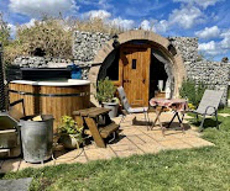 希尔内斯Romantic escape luxury Hobbit house with Hot tub!的后院,有桶,桌子,还有一座建筑