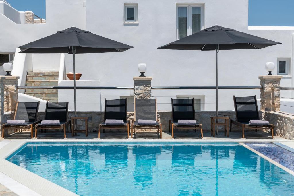 纳乌萨帕里米洛斯SPA酒店的大楼内一个带椅子和遮阳伞的游泳池
