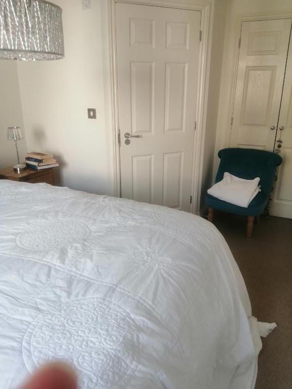BoxleyMaidstone Homestay的卧室配有白色的床和蓝色椅子