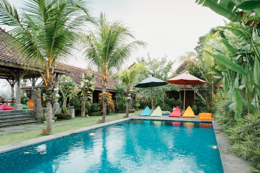乌布Nauna Villa Ubud的一座房子旁带五颜六色遮阳伞的游泳池