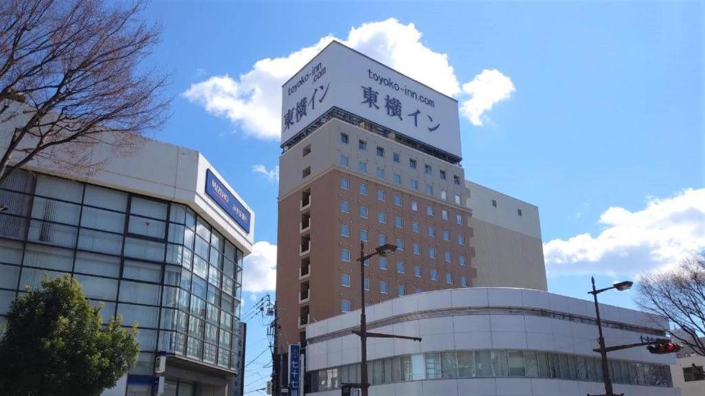磐城Toyoko Inn Iwaki Ekimae的一座高大的建筑,上面有标志