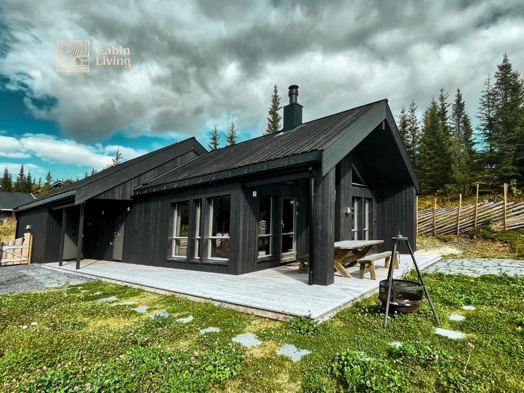SvingvollModern unique cabin fantastic location Skeikampen的黑房子,在田野上设有甲板