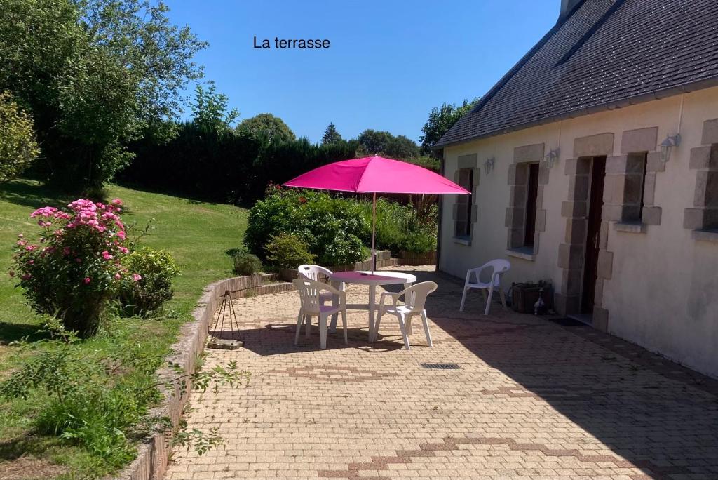 普卢贡旺Maison de campagne de plein pied.的院子里的一张桌子和椅子,上面有粉红色的雨伞
