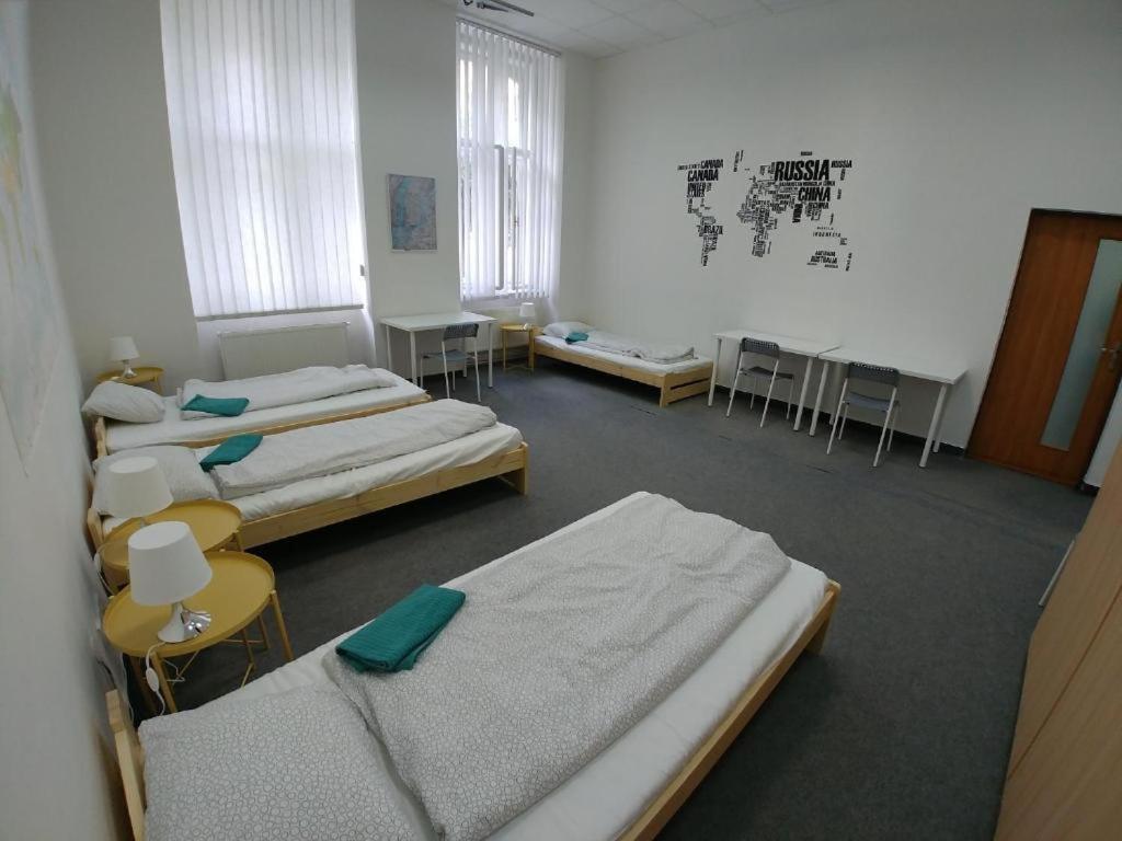 布尔诺ApartHostel Brno的带三张床和桌椅的房间