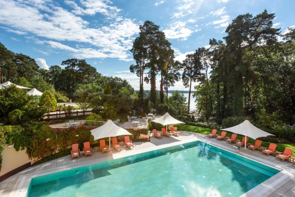 巴特萨罗皮斯库夫Precise Resort Bad Saarow - Golf & Spa的一个带椅子和遮阳伞的室外游泳池
