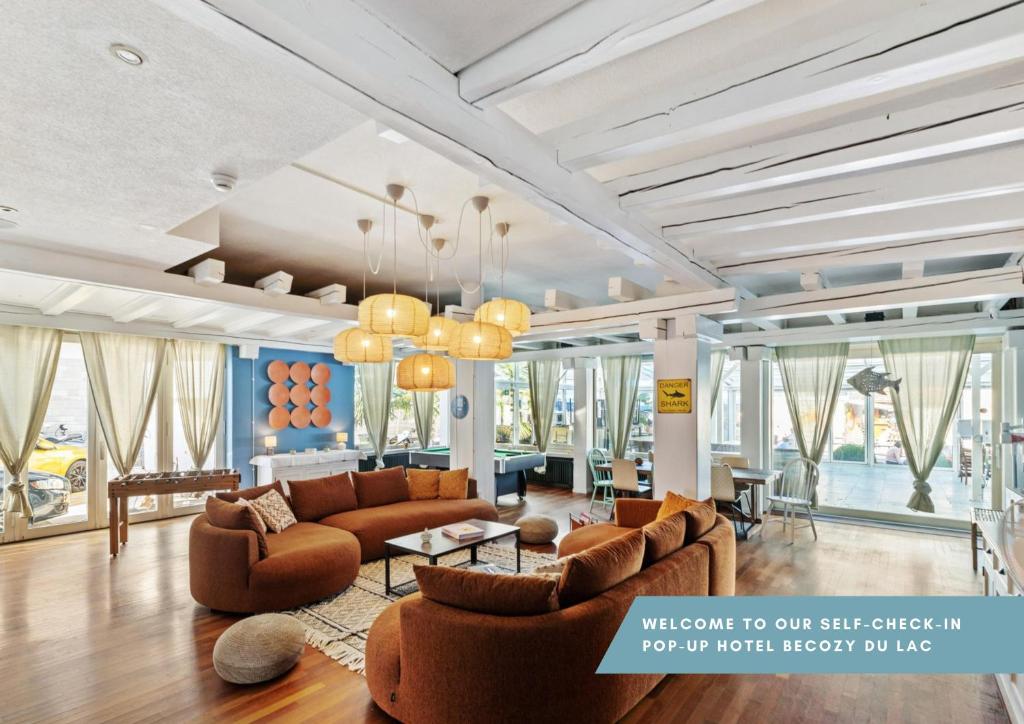 韦登斯维尔becozy du Lac Self-Check In Hotel Riviera Edition的带沙发和桌子的客厅以及窗户。