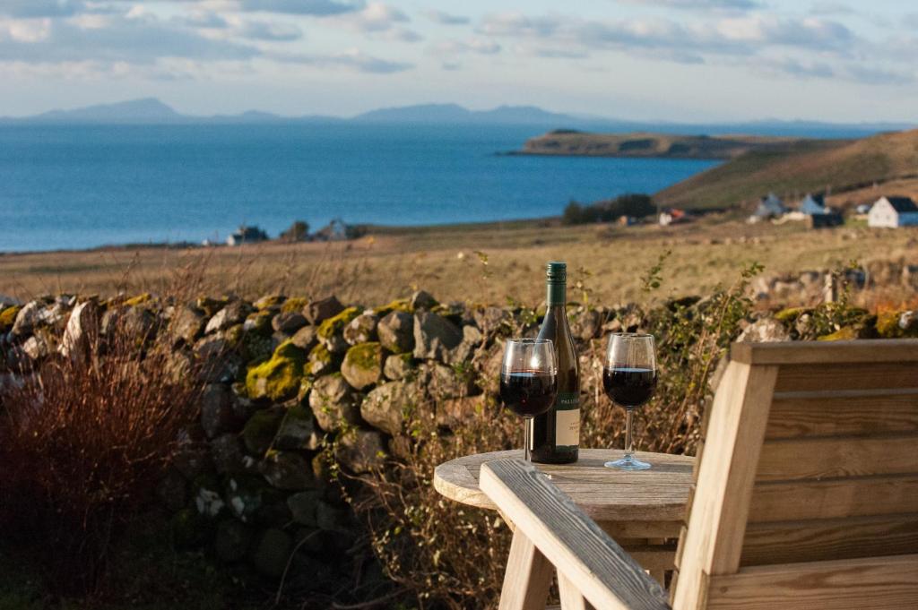 HallinAn Cala Beag Self Catering apartment on The Waternish Peninsula的一张桌子,上面放有两杯葡萄酒和一瓶