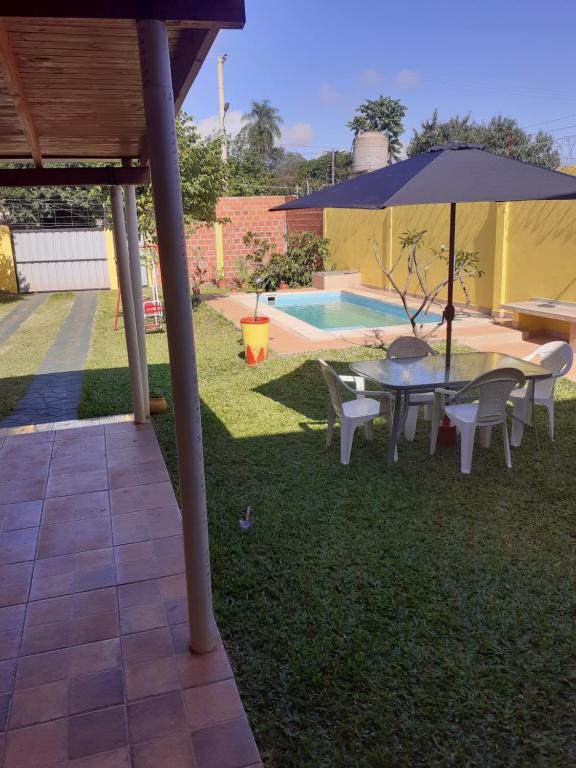 Villa LoncaLa Candela 1 casa的一个带桌子和遮阳伞的庭院,毗邻一个游泳池