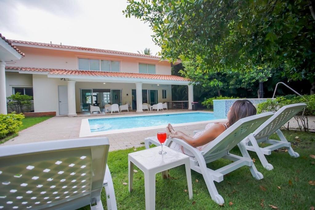 ParaísoImpresionante villa con piscina Metro Country Club的坐在草坪椅上的女人,喝一杯酒