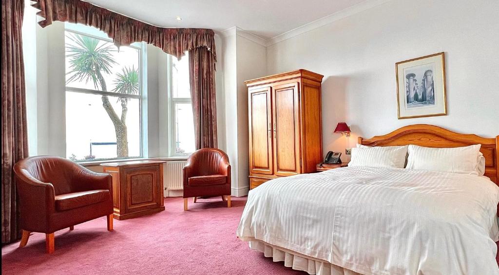 道格拉斯Promenade House的一间卧室配有一张床、两把椅子和一个窗户