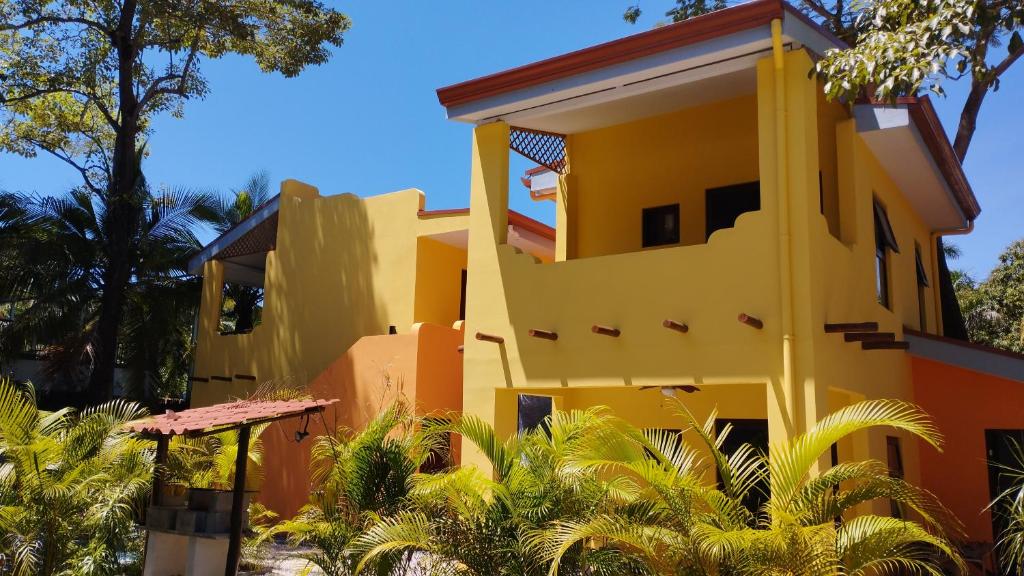 普拉亚弗拉明戈Hotel Tabasco的棕榈树前方的黄色房子