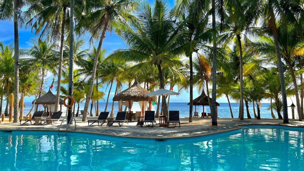 锡基霍尔锡基霍尔岛可可林海滩度假村的一座棕榈树和椅子的游泳池以及大海