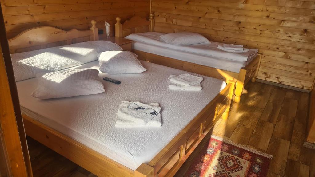 ChişcăuCabanuțele din Lemn的小木屋内的两张床,配有白色床单