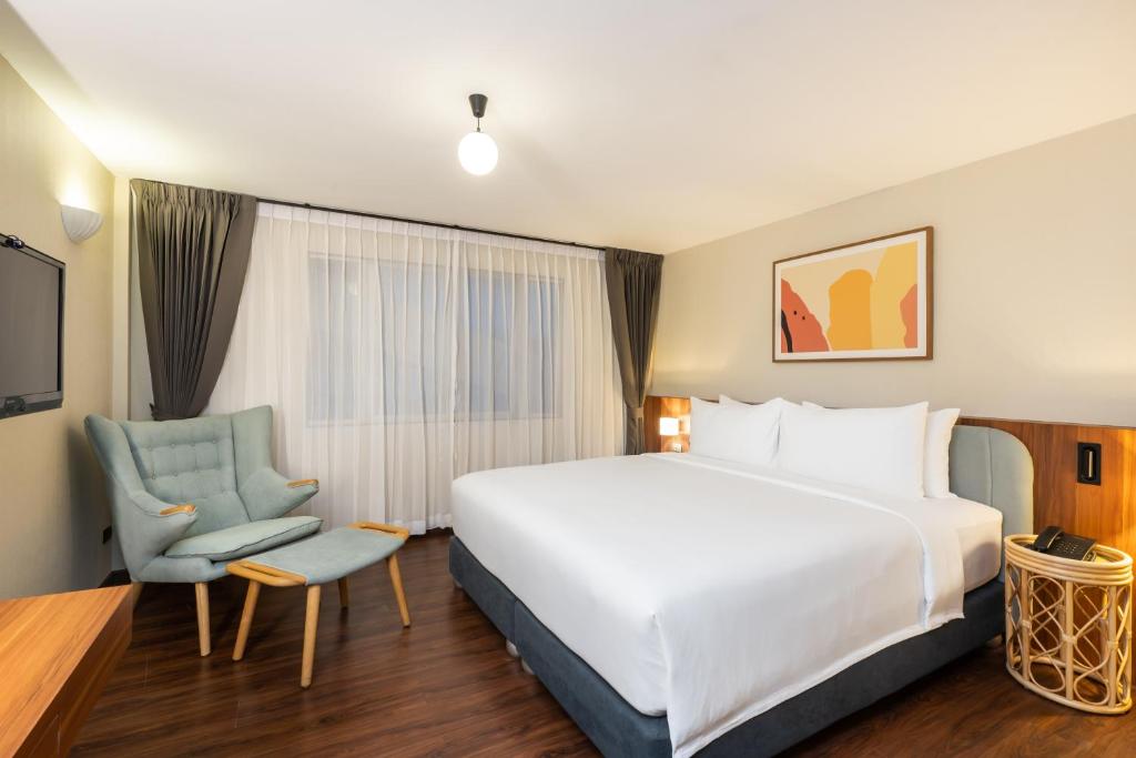 曼谷Arck Hotel的酒店客房带一张大床和一把椅子