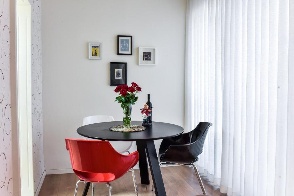 纳哈里亚SOKOLOV Vacation Boutique Apartments by the sea in nahariya的一间用餐室,配有黑桌子和红色椅子