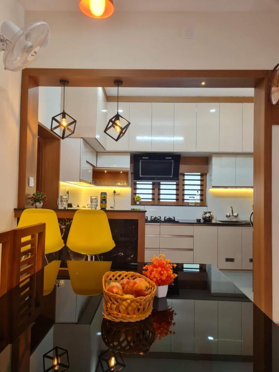 瓦亚纳德Milaano Orchids, Service Villa, Kammana Mananthavady的厨房配有黄色的椅子和一张带水果篮的桌子