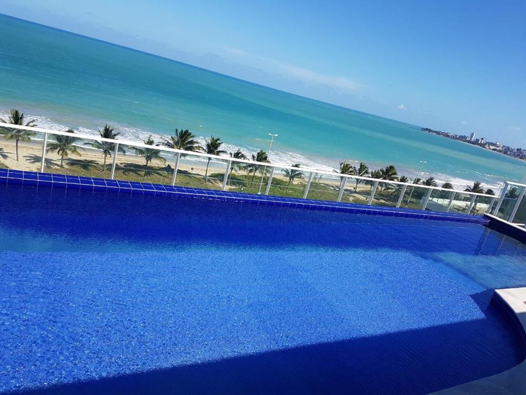 卡贝德卢Confortável Flat com piscina de borda infinita na cobertura的享有海滩景致的游泳池