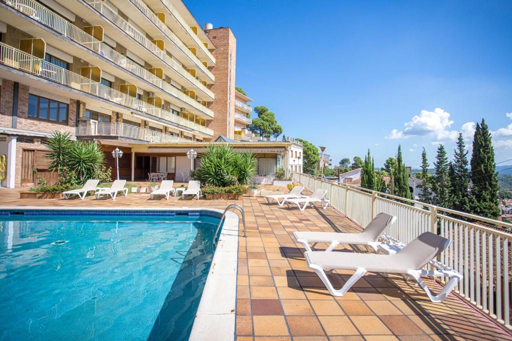 科贝拉罗布里加Can Fisa Hotel & Apartments的一座带躺椅的游泳池和一座建筑