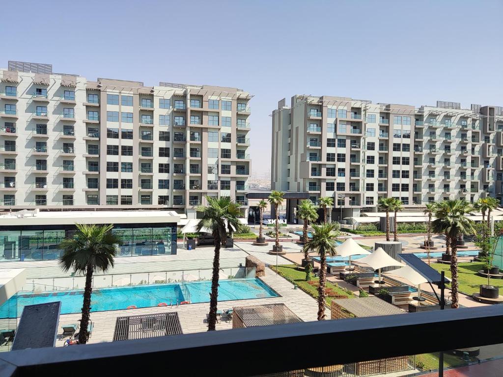 迪拜5*Amenities-2Br-15 min DxbApt,20min to Dubai Mall的享有带游泳池和棕榈树的度假村的景致