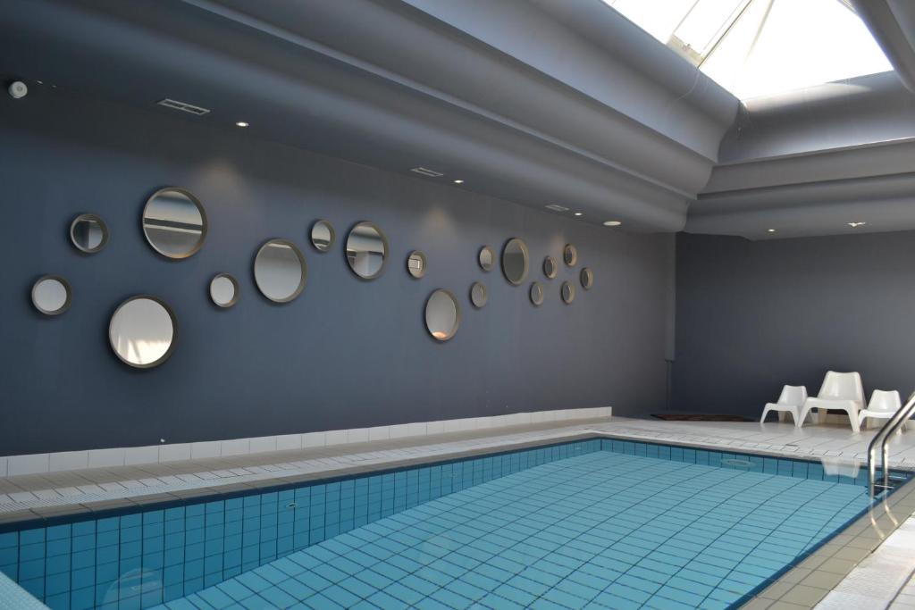 普雷法艾伊Logis Hôtel Restaurant Le Calluna的墙上镜子的游泳池