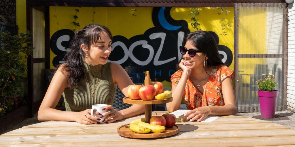 戈尔韦Snoozles Galway City Centre的两个女人坐在桌子上,拿着一盘水果