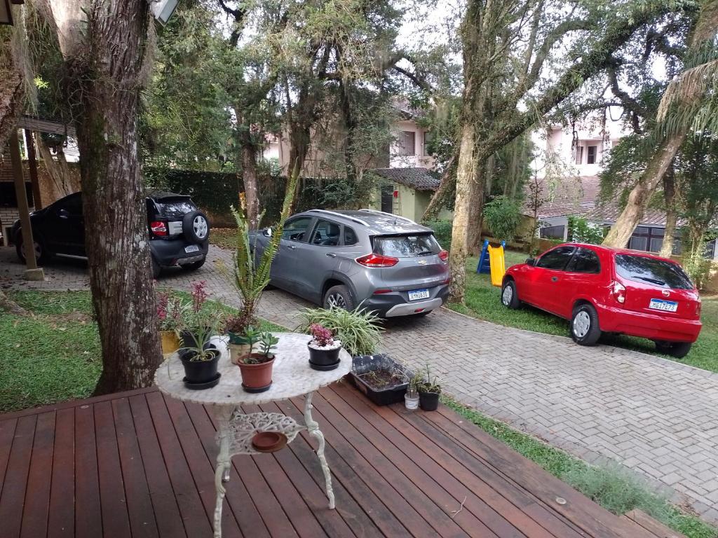 库里提巴Charming Home 2 min. from Barigui Park的甲板上摆放着盆栽的桌子,有两辆车