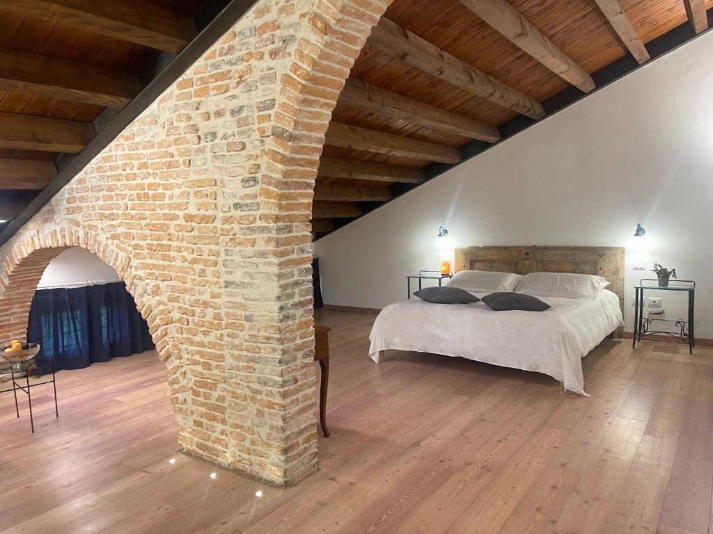 Monticello Conte OttoAlbaspina BioAgriturismo的一间设有砖墙和一张床的大卧室
