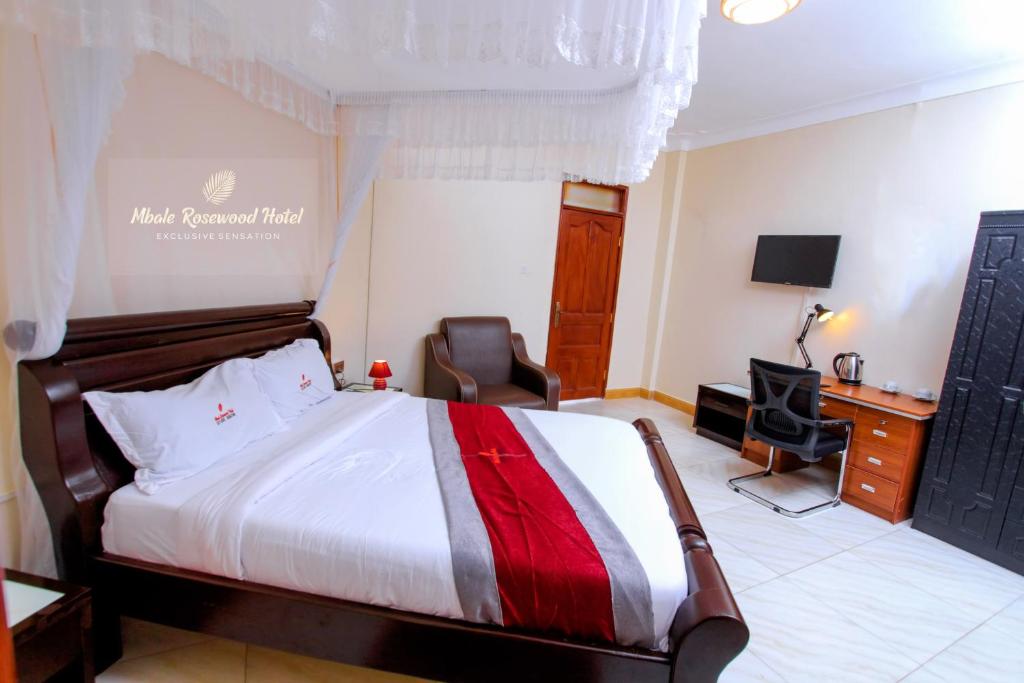 MbaleMbale Rosewood Hotel的酒店客房,配有一张床、一张桌子和椅子
