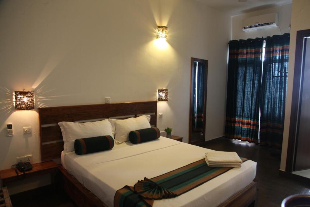 阿鲁甘湾维斯塔湾酒店的一间卧室配有一张带两盏灯的大型白色床。