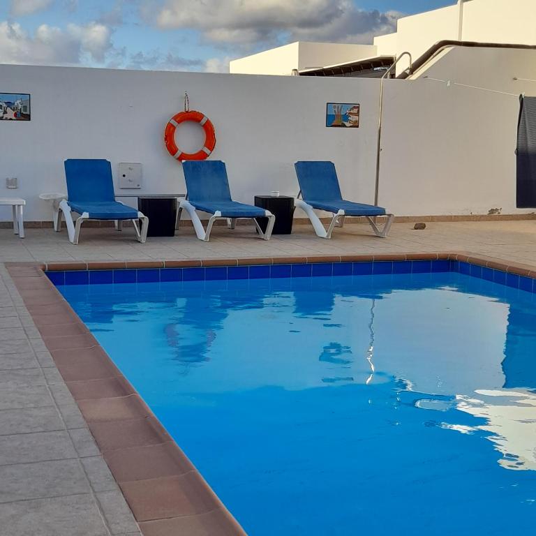普拉亚布兰卡Villa julima的一座游泳池旁设有两把蓝色椅子