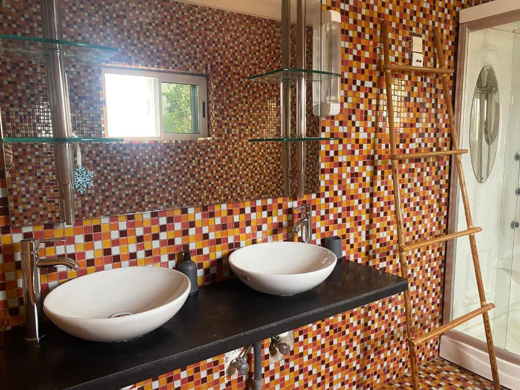 科托努L'Oasis Guesthouse的浴室设有黑色柜台上的两个盥洗盆