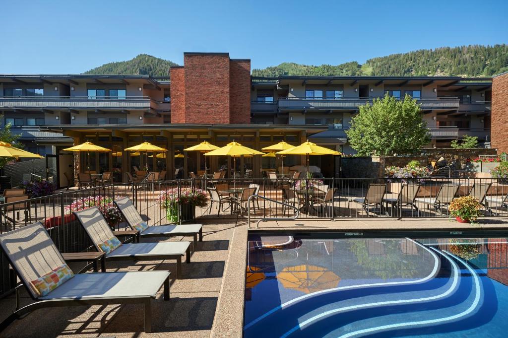 阿斯潘阿斯广场公寓酒店 的酒店设有带椅子和遮阳伞的游泳池