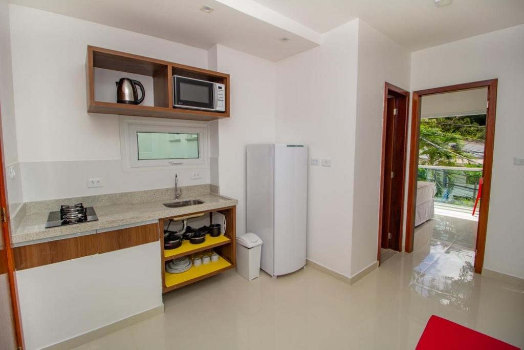 莫罗圣保罗Apart-Hotel Bella Vida Suítes e Apartamentos的白色的厨房配有冰箱和微波炉。
