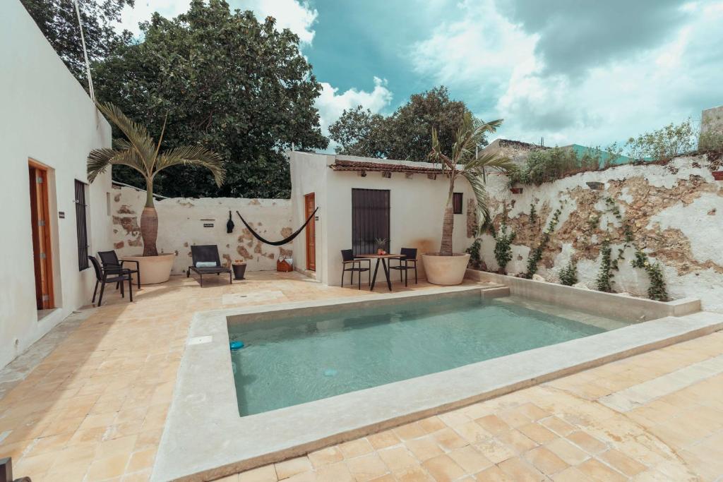 坎佩切Hotel Casa Piedad的庭院内的游泳池,配有椅子和墙壁