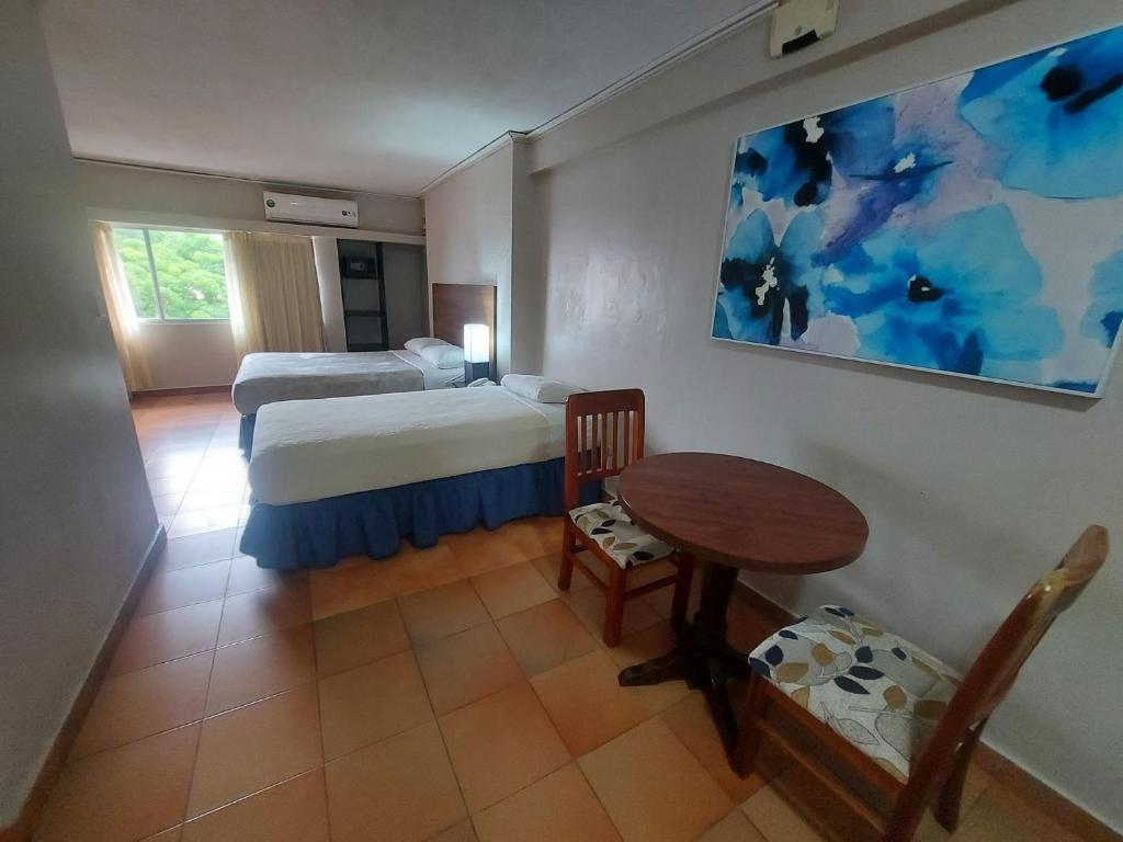 巴拿马城塔楼套房酒店的卧室配有1张床、1张桌子和1张桌子以及椅子。