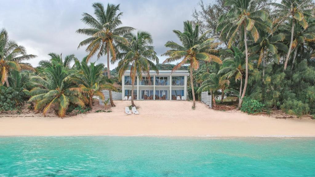 拉罗汤加Vaima Beachfront Apartments的棕榈树和水滩上的别墅
