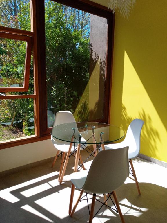 马德普拉塔casita moderna frente al bosque的窗户客房内的2把椅子和1张玻璃桌