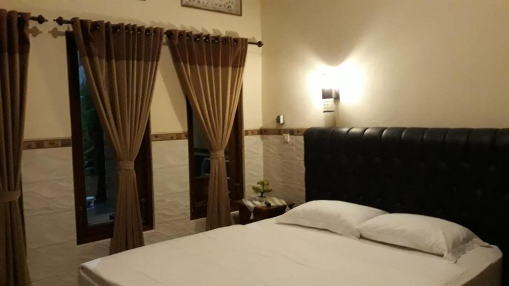 八丹拜Jepun Inn的一间卧室配有床、镜子和窗帘