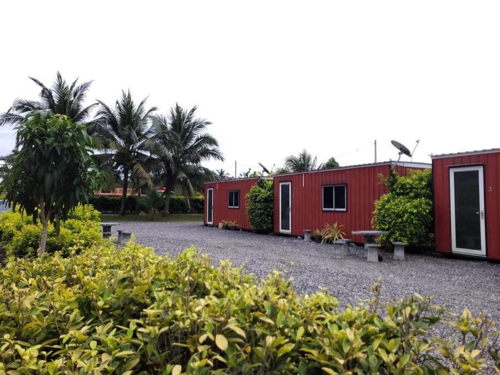 Tanjung KarangAsiaCamp - Cabin Sungai Sireh的一排种满树木和灌木的红色建筑