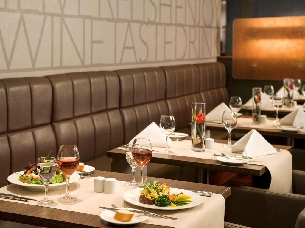 杜塞尔多夫杜塞尔多夫城西诺沃特酒店的餐厅设有2张桌子和葡萄酒